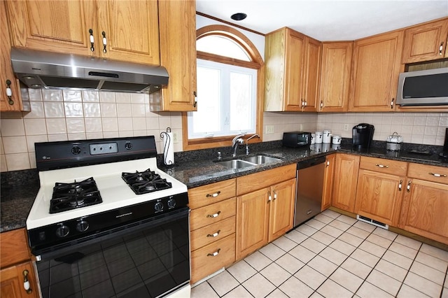kitchen featuring tasteful backsplash, a sink, under cabinet range hood, stainless steel appliances, and light tile patterned flooring