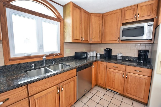 kitchen featuring a sink, light tile patterned floors, brown cabinets, and stainless steel appliances