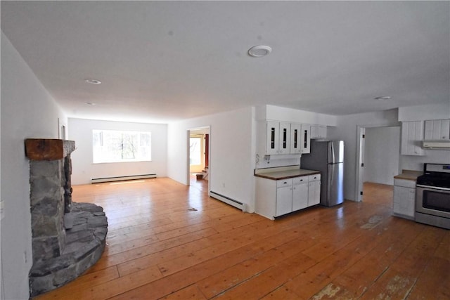 kitchen featuring a baseboard radiator, under cabinet range hood, white cabinets, and stainless steel appliances