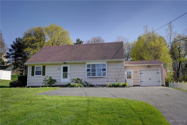 ranch-style home with an attached garage, fence, driveway, and a front yard