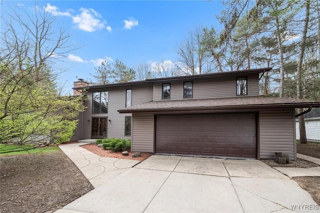 view of front of home with a garage, a chimney, and concrete driveway