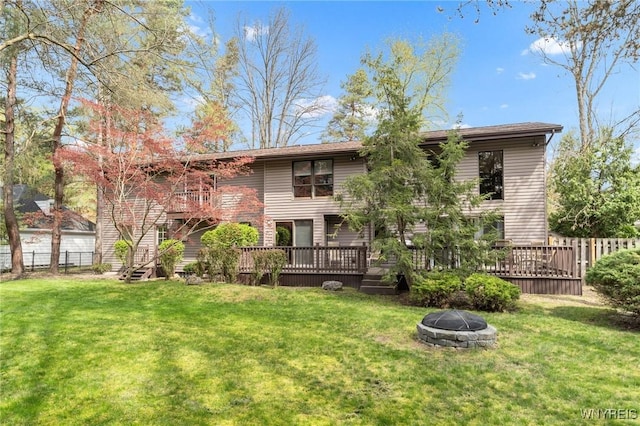 rear view of property featuring fence, a lawn, and a fire pit