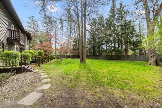 view of yard featuring a fenced backyard and a balcony