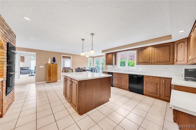 kitchen with brown cabinets, light countertops, decorative backsplash, a kitchen island, and black appliances