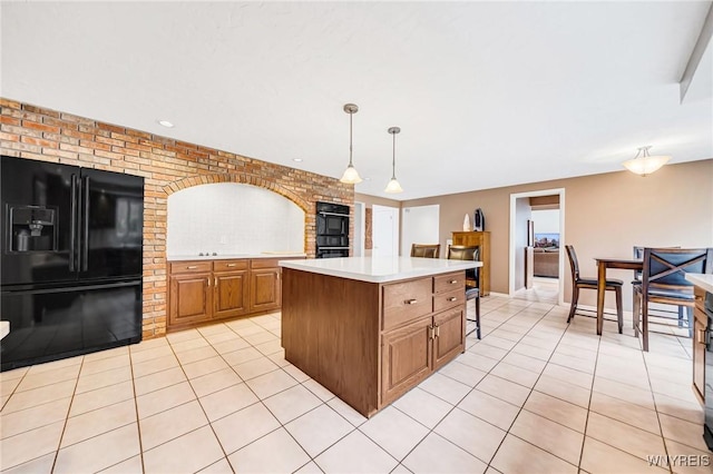 kitchen featuring light countertops, light tile patterned floors, a center island, and black appliances