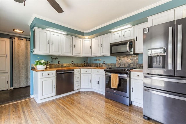 kitchen with a sink, white cabinets, stainless steel appliances, and butcher block countertops