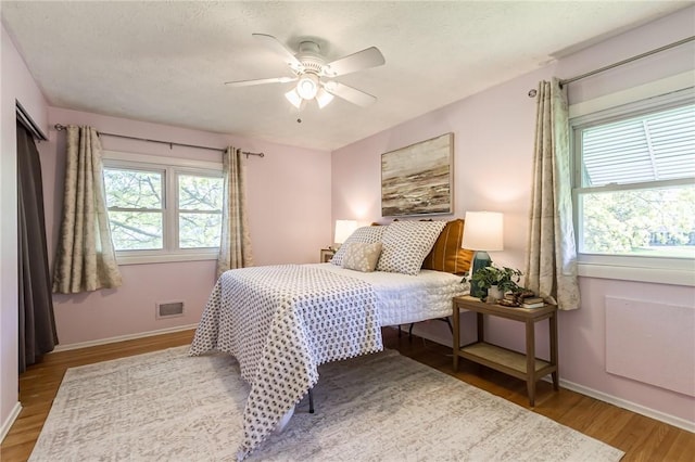 bedroom featuring baseboards, wood finished floors, and visible vents