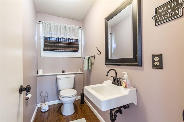 bathroom featuring a sink, baseboards, toilet, and wood finished floors
