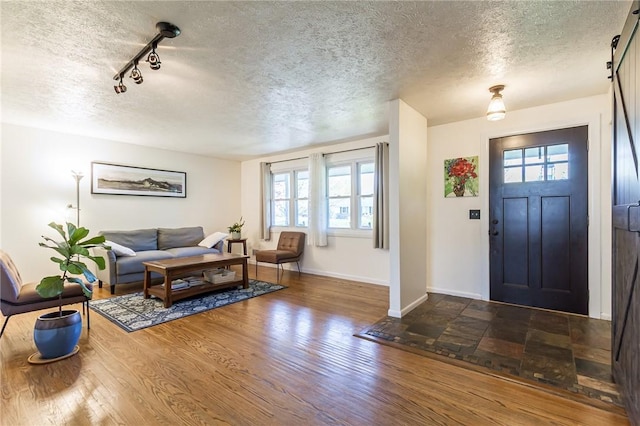 foyer featuring baseboards, a textured ceiling, and wood finished floors