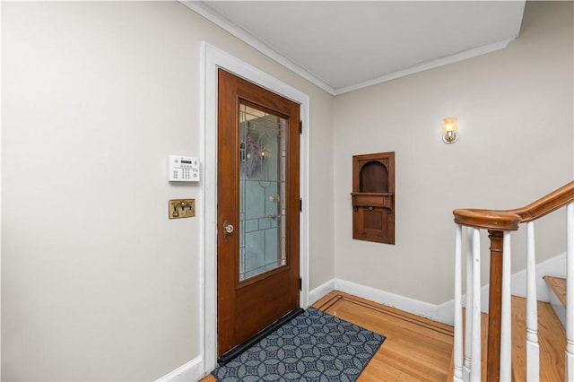 foyer entrance with baseboards, ornamental molding, wood finished floors, and stairway