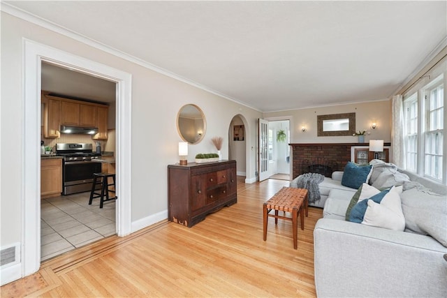 living area featuring arched walkways, a healthy amount of sunlight, and ornamental molding