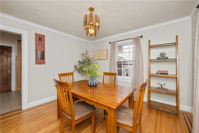dining room featuring baseboards, a notable chandelier, ornamental molding, and light wood finished floors