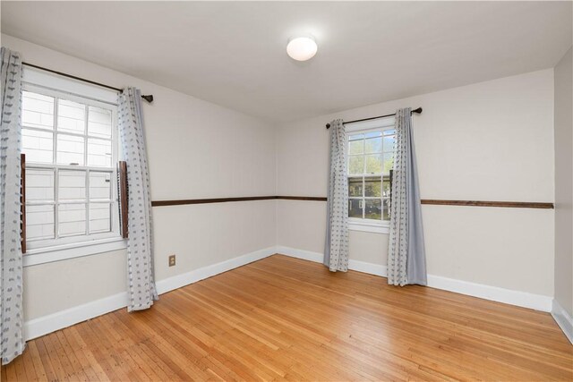 spare room featuring baseboards and light wood-style floors