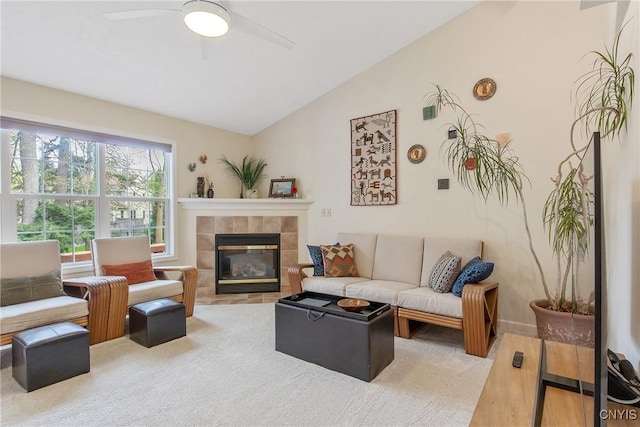 living room with a ceiling fan, lofted ceiling, and a tile fireplace