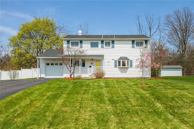 traditional-style house with a chimney, a garage, fence, aphalt driveway, and a front lawn