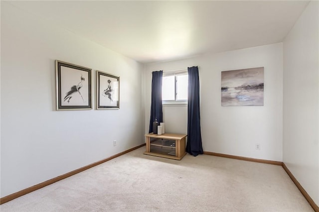 unfurnished room featuring baseboards and light colored carpet