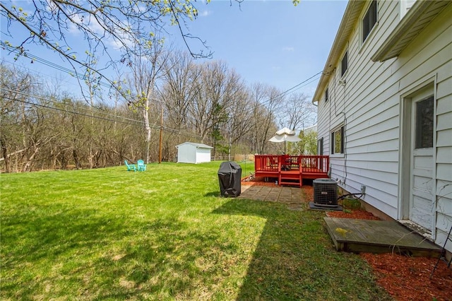 view of yard featuring a storage shed, central air condition unit, an outbuilding, and a deck