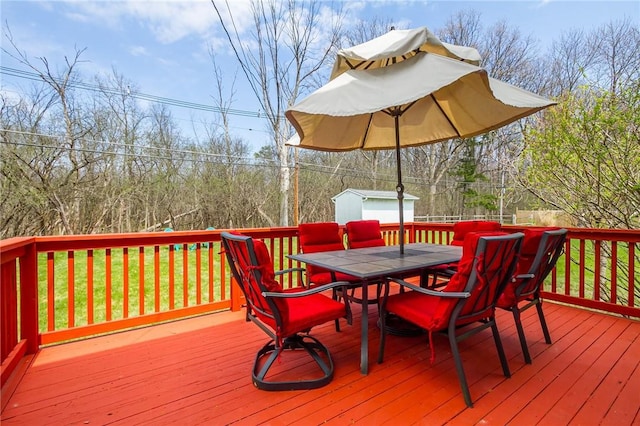 deck featuring outdoor dining area, an outbuilding, and a storage unit
