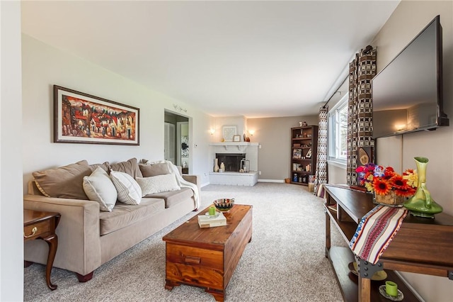 carpeted living area featuring baseboards and a fireplace with raised hearth