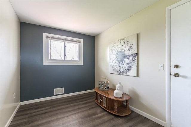 empty room featuring baseboards, visible vents, and dark wood finished floors