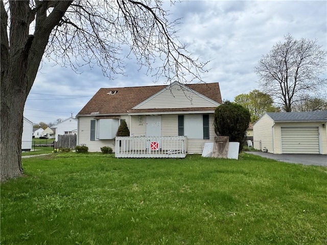 view of front facade featuring driveway, a front yard, an outbuilding, a garage, and a shingled roof