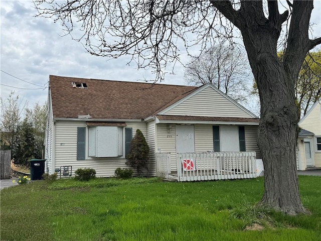 view of front of house featuring a front lawn, roof with shingles, and covered porch