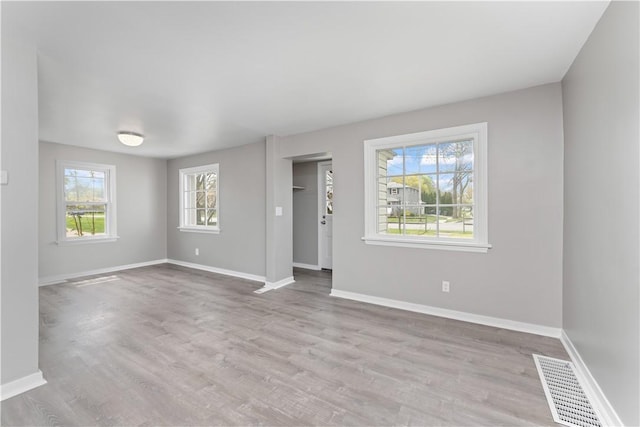 unfurnished living room featuring baseboards, visible vents, and wood finished floors