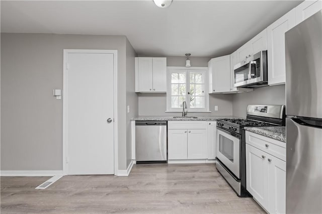kitchen with light wood-type flooring, a sink, white cabinetry, and appliances with stainless steel finishes