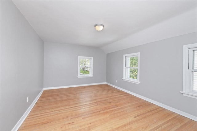 unfurnished room with baseboards, plenty of natural light, light wood finished floors, and lofted ceiling