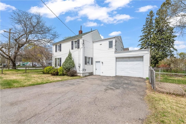 view of home's exterior featuring driveway, a chimney, a lawn, fence, and an attached garage