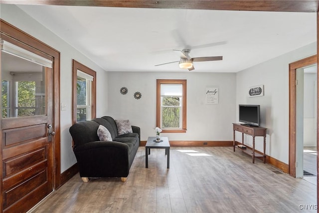 living room with baseboards, a ceiling fan, and light wood finished floors