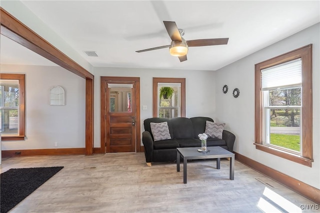 living area with ceiling fan, baseboards, visible vents, and a wealth of natural light
