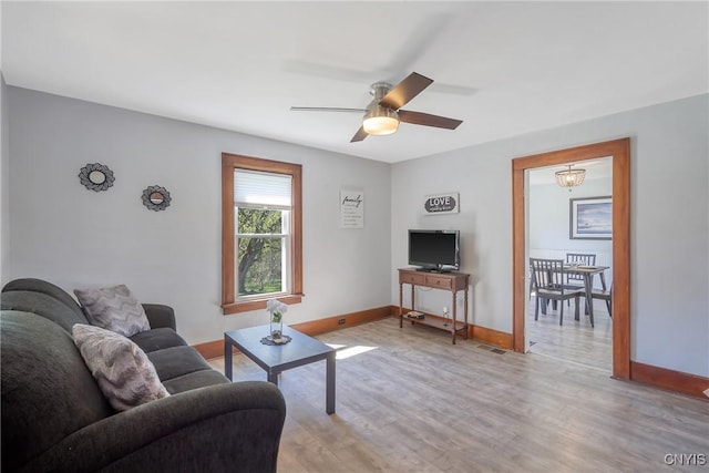 living area with baseboards, visible vents, ceiling fan, and light wood-style floors