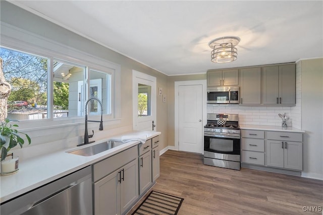 kitchen featuring decorative backsplash, plenty of natural light, a sink, gray cabinetry, and stainless steel appliances
