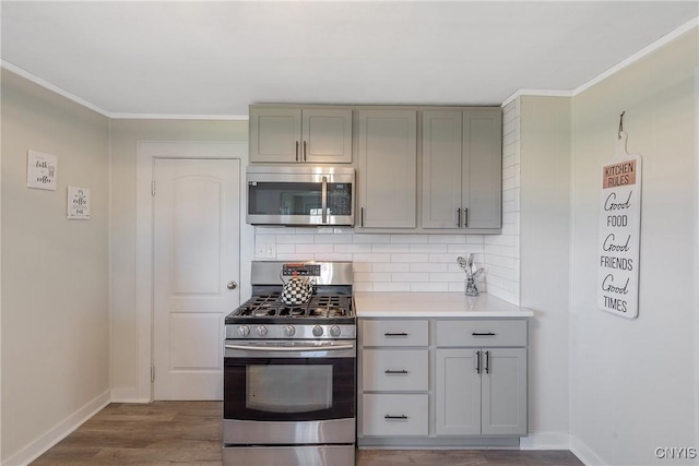 kitchen with baseboards, gray cabinets, appliances with stainless steel finishes, and backsplash