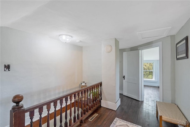 hallway with visible vents, hardwood / wood-style floors, baseboards, attic access, and an upstairs landing