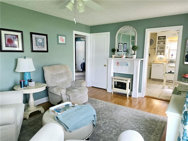 living room featuring baseboards, a ceiling fan, and wood finished floors