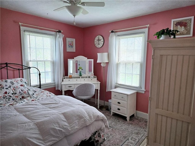 bedroom featuring a ceiling fan, baseboards, and multiple windows