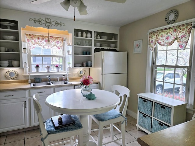 kitchen with a sink, a ceiling fan, light tile patterned floors, and freestanding refrigerator