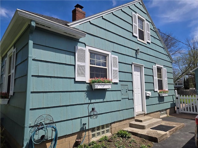 view of side of home featuring fence, a chimney, and entry steps