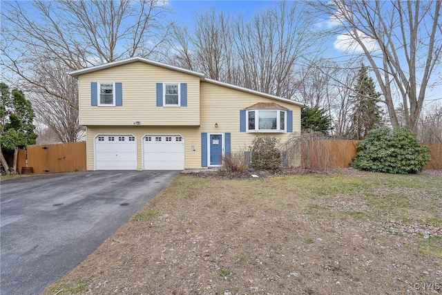 tri-level home with fence, an attached garage, and driveway