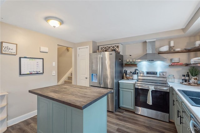 kitchen with butcher block countertops, open shelves, appliances with stainless steel finishes, and wall chimney range hood