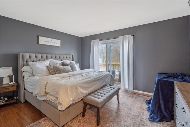 bedroom featuring access to outside, baseboards, and wood finished floors