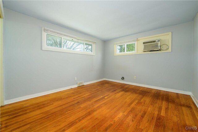 216 Pine Grove St, Syracuse, NY 13210 - unfurnished room featuring an AC wall unit, baseboards, wood finished floors, and visible vents