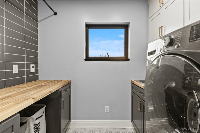 clothes washing area featuring washer / dryer, baseboards, and cabinet space
