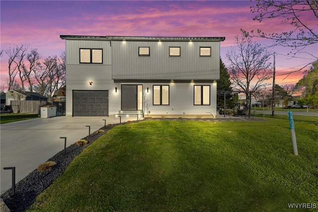 modern home featuring concrete driveway, fence, a front yard, and a garage