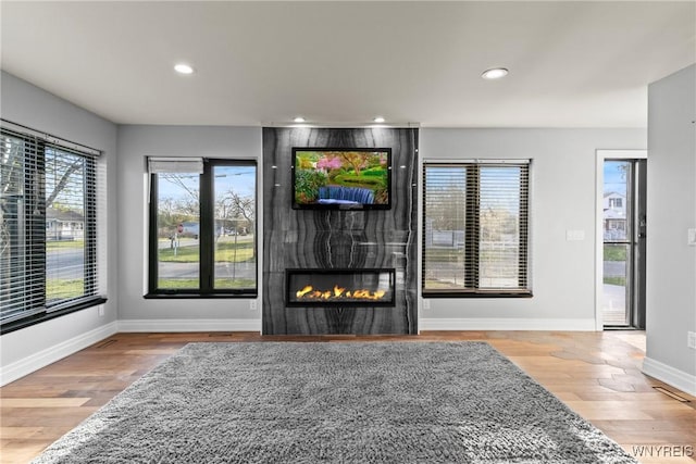 living room with recessed lighting, baseboards, a large fireplace, and wood finished floors