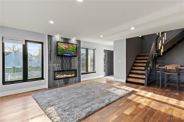 living room with a fireplace, stairs, wood finished floors, baseboards, and recessed lighting