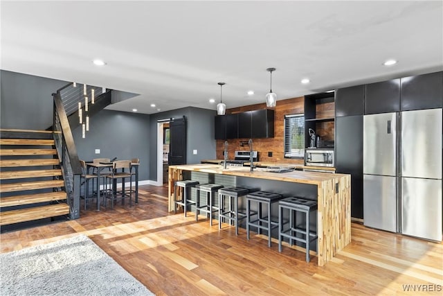 kitchen with light countertops, stainless steel appliances, a barn door, and light wood finished floors