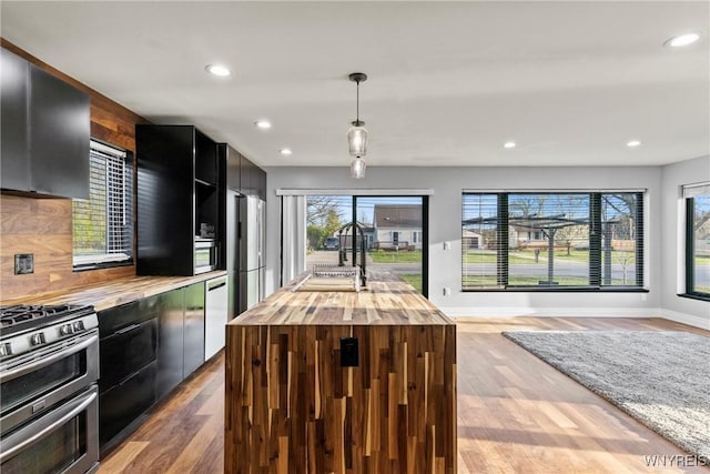 kitchen featuring a sink, dark cabinets, wooden counters, stainless steel appliances, and recessed lighting